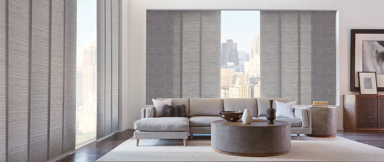 A large living room with tall windows featuring Skyline® Gliding Window Panels; Fabric: Maya  Color: Zanzibar Grey